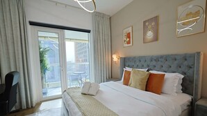 Ein Hotelzimmer mit einem großen Bett, einem Sessel, einem Schreibtisch und Blick auf die Stadt durch das Fenster.