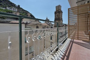 A balcony with a metal railing overlooking a building with a clock tower. - The Bell Tower Clock with terrace (Minori)