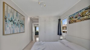 A hotel room with a large bed, white walls, a ceiling light, a painting, and a window with a view. - Sun And Green, Heated Pool, 3 Rooms, Air C (San Miguel de Abona)