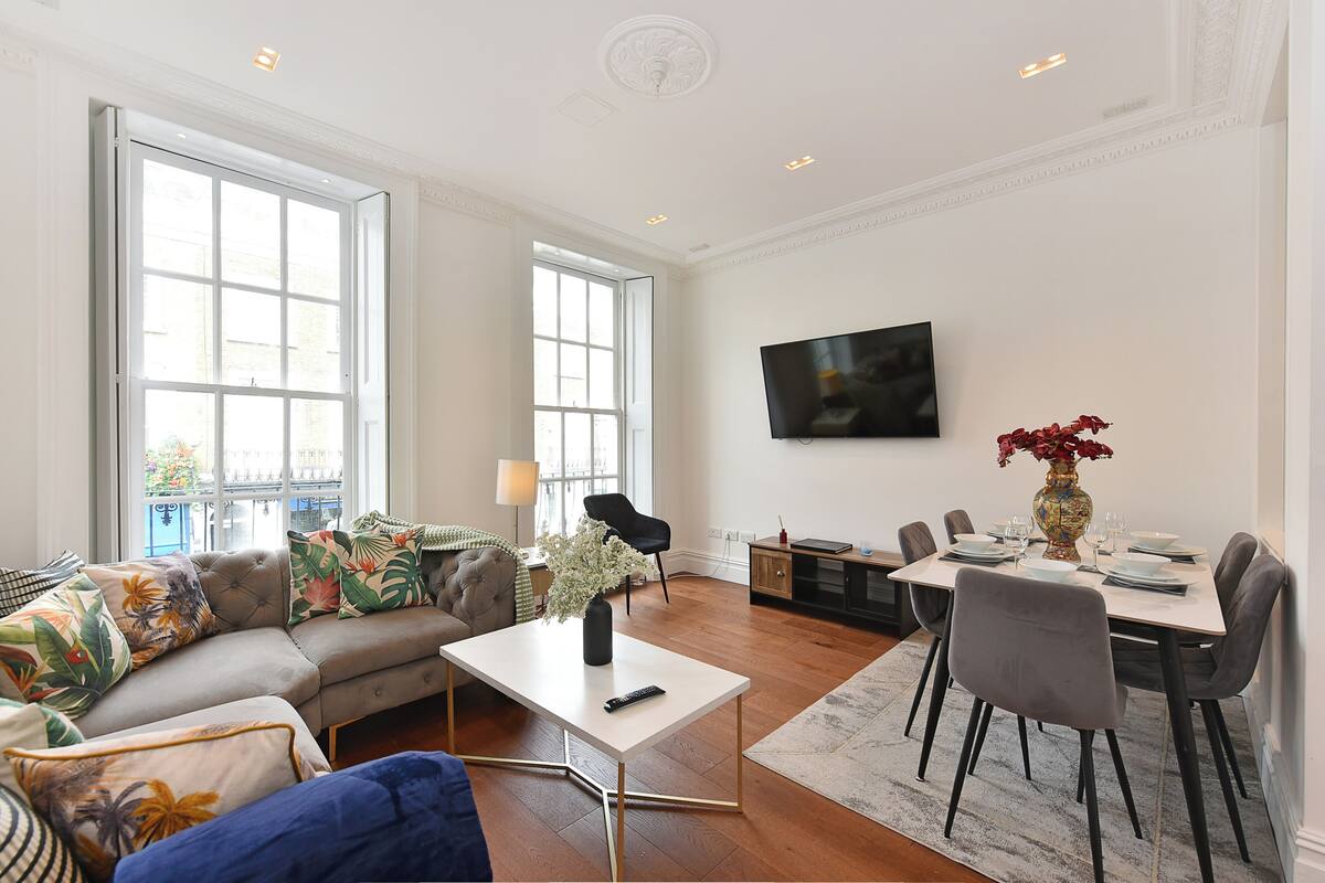 A spacious living room with a sofa, coffee table, and dining area with chairs and a TV.