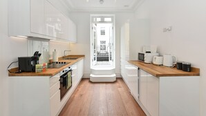 Una cocina moderna con armarios blancos, encimera de madera y vistas al exterior por una ventana.