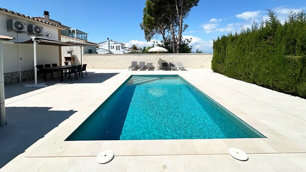 Une piscine rectangulaire à l’eau d’un bleu limpide, entourée d’une terrasse carrelée. On y trouve des chaises longues et un espace barbecue.