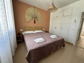 Ein Schlafzimmer mit Bett, Kleiderschrank, Deckenventilator und Nachttisch.