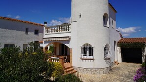 Un bâtiment blanc doté d’une tour ronde, d’un balcon et d’un patio aménagé avec du mobilier d’extérieur.