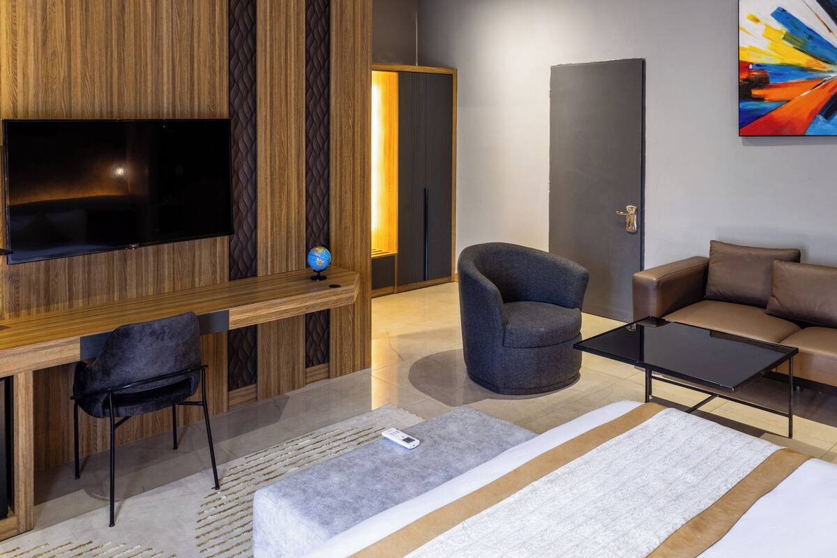 A modern living room with a flat-screen TV, a comfortable sofa, a chair, and a coffee table.
