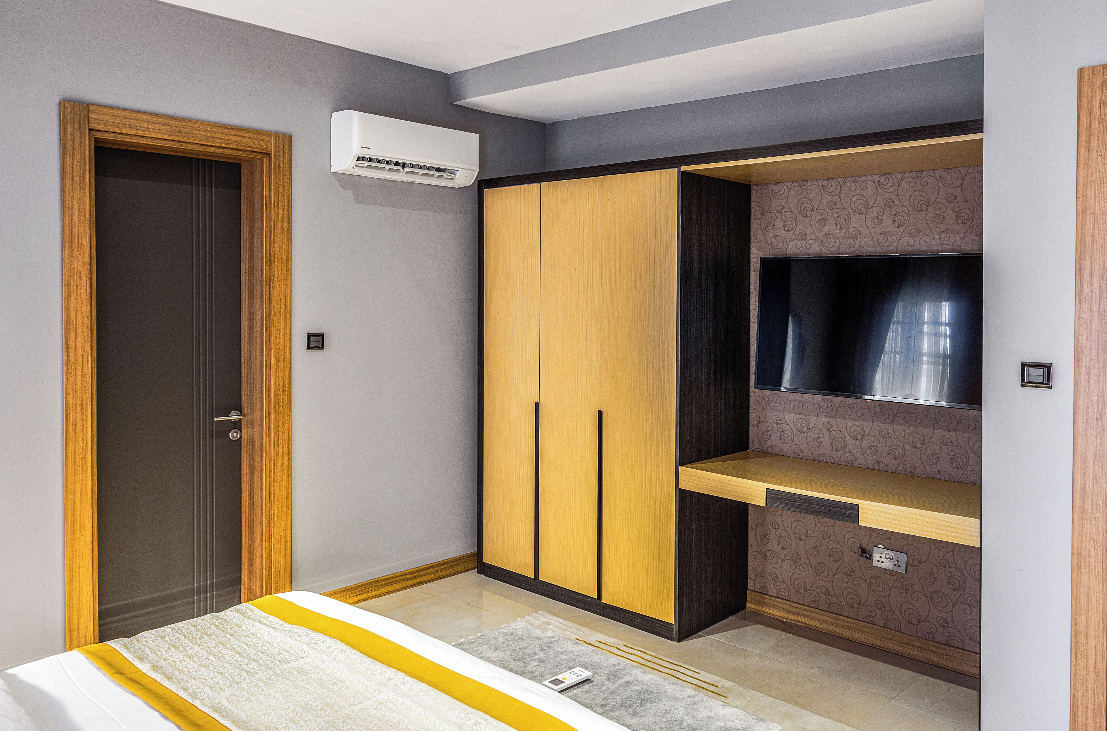 A bedroom with a wardrobe, a bed, and a built-in TV shelf.