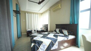A hotel room with a large bed, a smaller bed, a ceiling fan, and a window with curtains. - amp lodge (Kumasi)