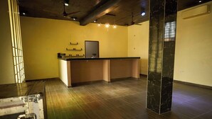 A reception area with a counter, a large pillar, and a wall-mounted mirror. - amp lodge (Kumasi)
