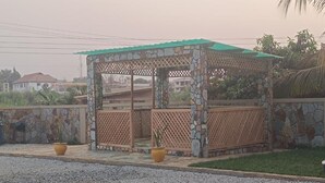 A gazebo with a stone and lattice design, surrounded by a stone wall and potted plants. - amp lodge (Kumasi)