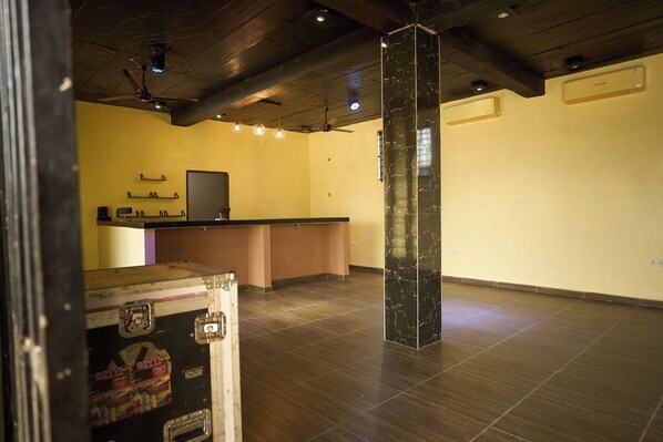 A spacious room with a wooden ceiling, a reception desk, and a large pillar. - amp lodge (Kumasi)