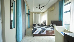 A bedroom with a bed, a desk, a chair, a ceiling fan, and a window with curtains. - amp lodge (Kumasi)