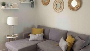 Een moderne woonkamer met een grijze modulaire bank, een klein rond salontafeltje en decoratieve spiegelwanden.