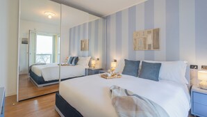 Ein modernes Hotelzimmer mit einem großen Bett, Nachttischen, einem Spiegel und Blick ins Freie.