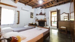 A room with two beds, a wooden ceiling, a fireplace, and a mirror.