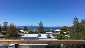 A residential area with houses, solar panels, and a clear view of the ocean and mountains in the distance. - 6 Bedroom House Swansea (au) (Swansea)