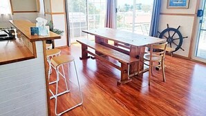 A wooden dining table with benches, a bar area, and a ship's wheel on the wall. - 6 Bedroom House Swansea (au) (Swansea)