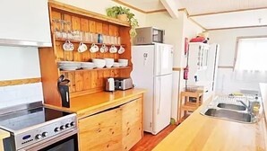 A compact kitchen with wooden cabinets, a built-in oven, a microwave, and a sink. - 6 Bedroom House Swansea (au) (Swansea)