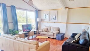 A living room with a sofa, a black couch, a coffee table, and a TV. - 6 Bedroom House Swansea (au) (Swansea)
