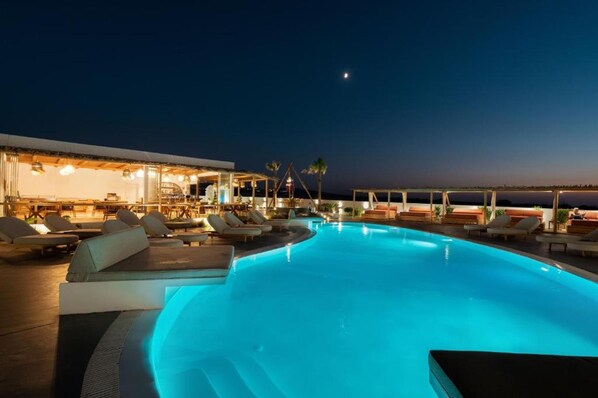 Un espace aménagé au bord de la piscine, avec des chaises longues et un bar qui ouvre le soir.