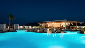 A poolside area with lounge chairs and a bar area. - Amethyst Luxury Suites - Oia Family Suite (Santorini)