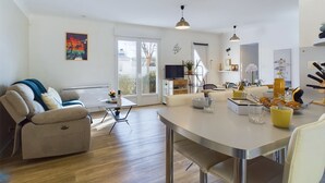 A spacious living area with a sofa, a dining table, and a kitchen area in the background. - Bourg d'Olonne s/Mer, charming house for 6 people (Les Sables-d´Olonne)