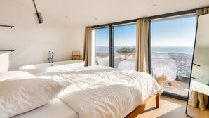 A bedroom with a large bed, a bathtub, and a view of the sea. - Pool, view and beach access, 6 adults/2 children (La Guérinière)