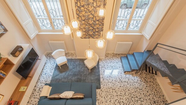 A spacious living area with a sofa, a chair, and a staircase. - Cinque Giornate 70 Suites by Rent all Como (Como)