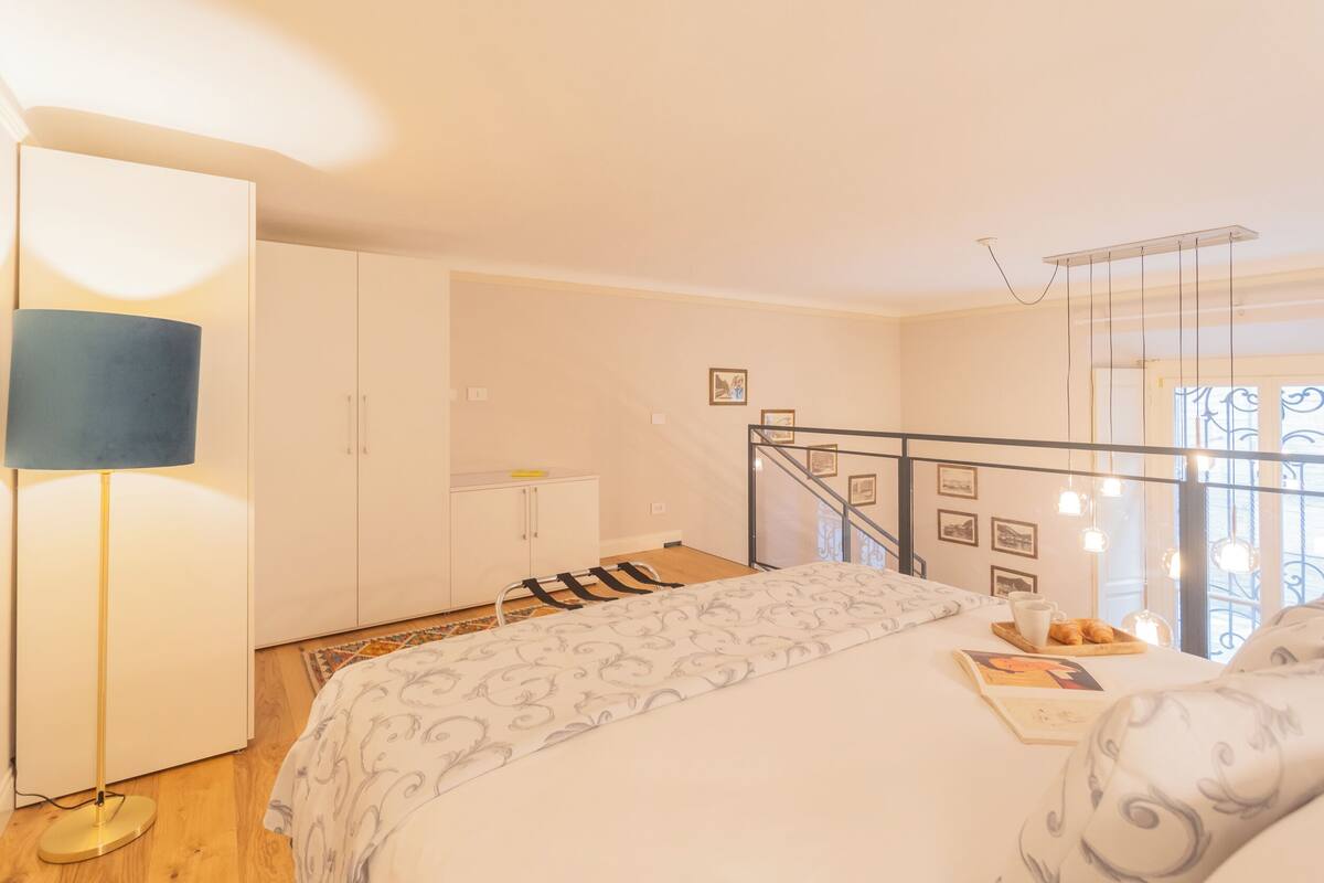 Un dormitorio con cama, mesita de noche, lámpara y vistas a un balcón.