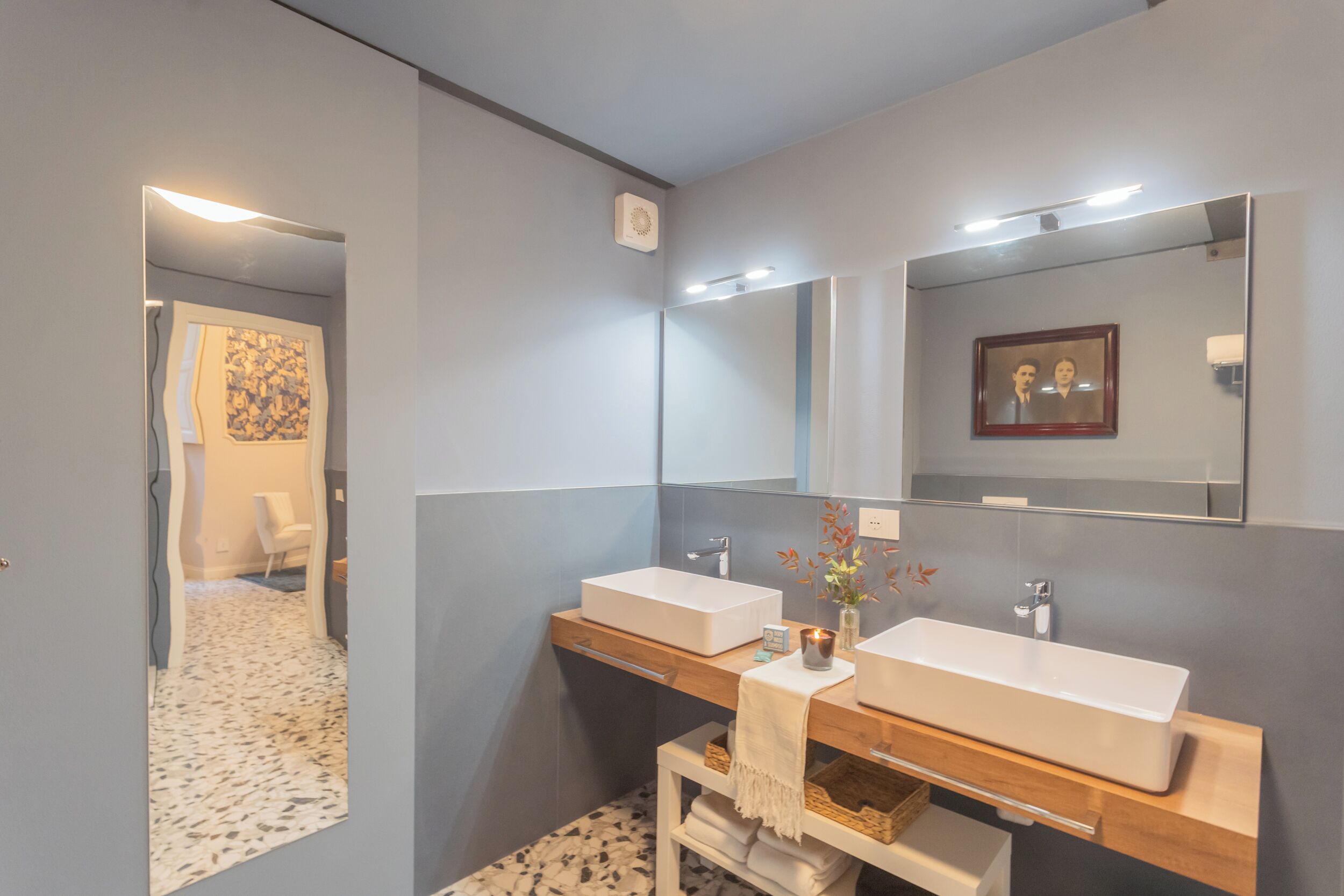 A modern bathroom with two sinks, a mirror, and a small table with a towel.