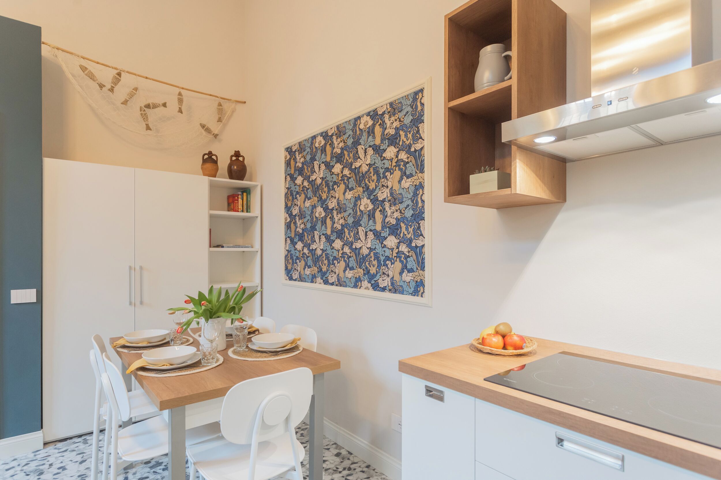 A modern kitchen with white cabinetry, a dining table set for four, and a decorative wall piece.