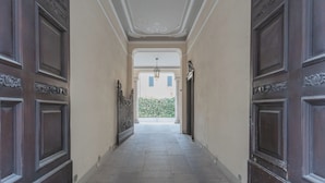 A hallway with dark wooden doors, light-colored walls, and a tiled floor. - Cinque Giornate 70 Suites by Rent all Como (Como)