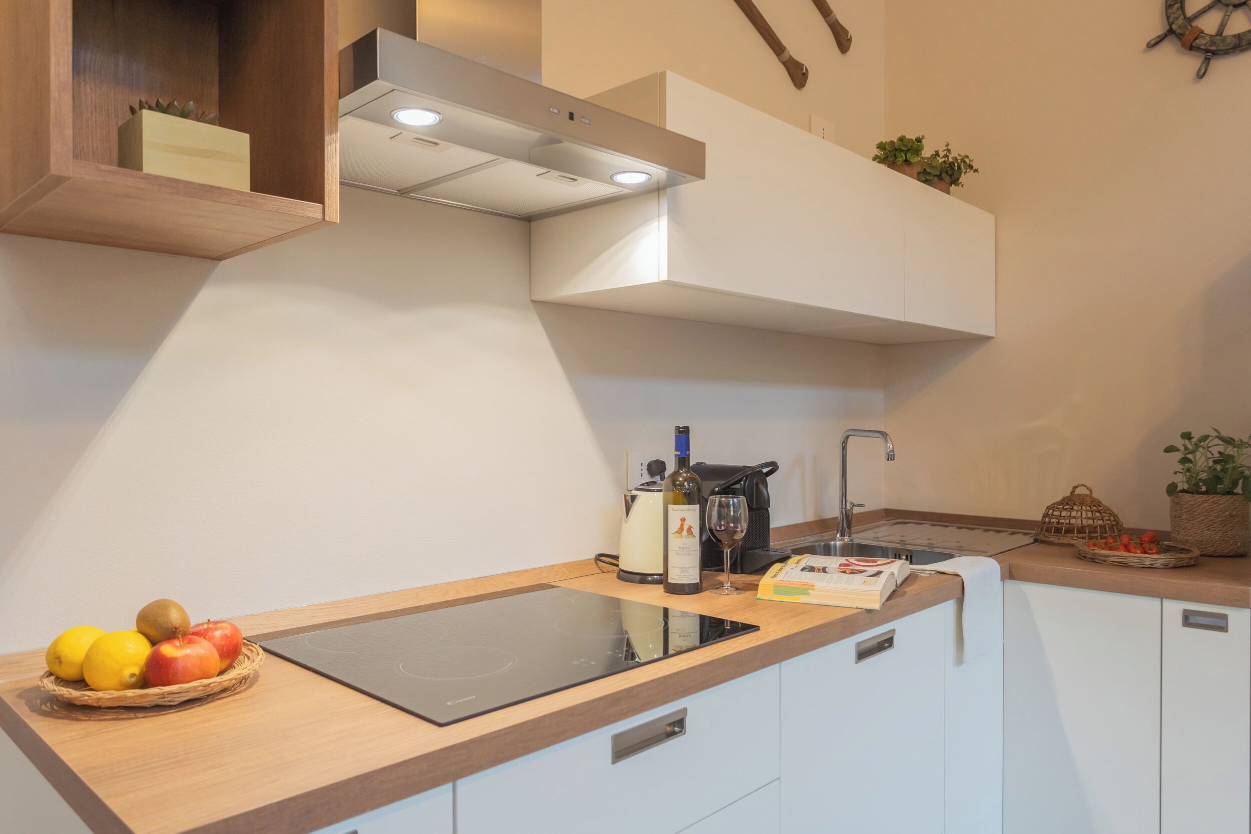 A modern kitchen with a built-in induction cooktop, white cabinets, and a wooden countertop.