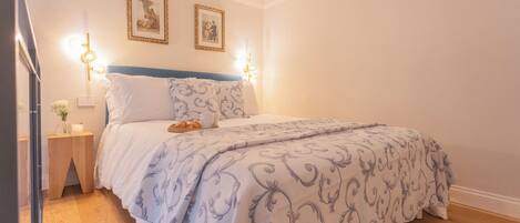 A bedroom with a bed, bedside tables, and wall-mounted lights.