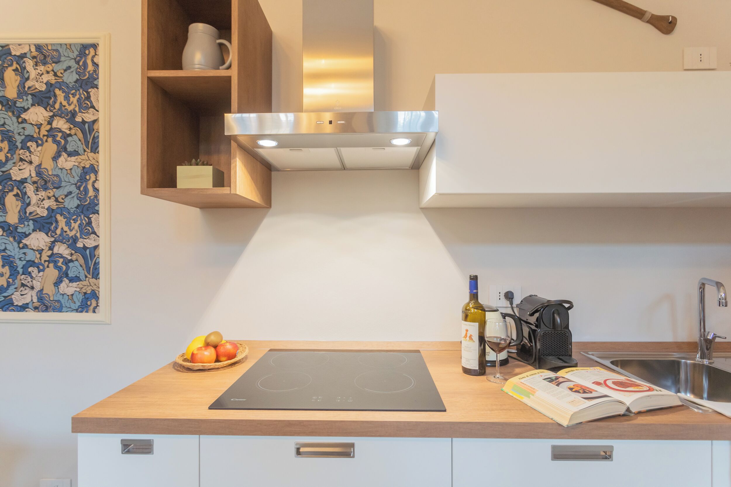 Une cuisine moderne équipée d’une plaque de cuisson à induction intégrée, d’une machine à café et d’une bouteille de vin.