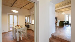 A spacious kitchen with a dining area, a staircase leading to another level, and a living room with a sofa and a TV. - Stunning home in Spello with WiFi (Spello)