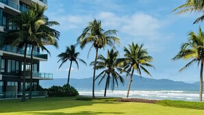 A modern hotel with a view of the ocean and palm trees.