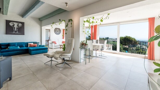 A spacious living area with a blue sofa, a white armchair, and a dining table with chairs. There is a balcony with a view of the landscape. - TOP VILLA PALOMA ANTIBES Vue Mer, Montagne, FIBRE, CLIME, POOL (Antibes)