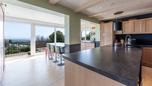 A modern kitchen with a large island, wooden cabinets, and a view of the outdoors. - TOP VILLA PALOMA ANTIBES Vue Mer, Montagne, FIBRE, CLIME, POOL (Antibes)