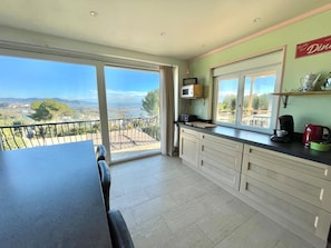 Enjoy meals with a view at this kitchen's dining table, overlooking the surrounding landscape.
