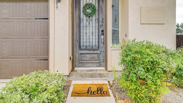 A residential entrance with a wooden garage door, a metal gate, a doormat with "hello" written on it, and a wreath on the door. - 8 Mi to the Galleria: Home w/ Balcony + Yard (Houston)