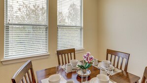 A dining table set with white plates, bowls, and cups, flanked by wooden chairs, with a vase of flowers in the center. - 8 Mi to the Galleria: Home w/ Balcony + Yard (Houston)