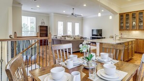 A spacious living area with a dining table set for four, a kitchen with wooden cabinets, and a staircase leading to an upper floor. - 8 Mi to the Galleria: Home w/ Balcony + Yard (Houston)