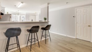 A modern kitchen with a bar area, wooden flooring, and a white door. - 8 Mi to Downtown: Atlanta Townhome! (Atlanta)