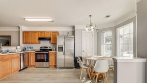 A modern kitchen with wooden cabinets, stainless steel appliances, and a dining area with a table and chairs. - 8 Mi to Downtown: Atlanta Townhome! (Atlanta)