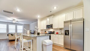 Une cuisine moderne avec des armoires blanches, des appareils en acier inoxydable et un plancher en bois.