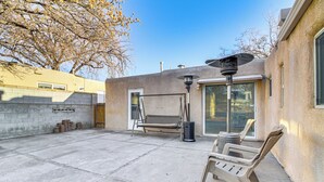 A patio area with a swing set, outdoor seating, and a lamp post. - Cozy Home w/ Grill & Games in Albuquerque! (Albuquerque)