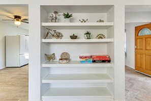 A white shelving unit with decorative items and board games. - Balloon Fiesta Stay w/ Heated Patio & Fire Pit (Albuquerque)