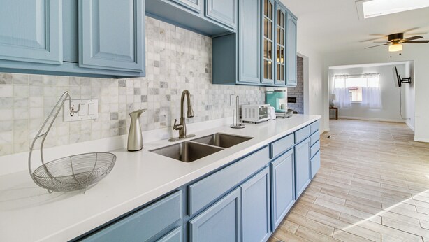A kitchen with blue cabinets, a white countertop, and a stainless steel sink. - Cozy Home w/ Grill & Games in Albuquerque! (Albuquerque)