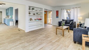 A spacious living area with a wooden floor, a sofa set, a coffee table, and a bookshelf. - Cozy Home w/ Grill & Games in Albuquerque! (Albuquerque)
