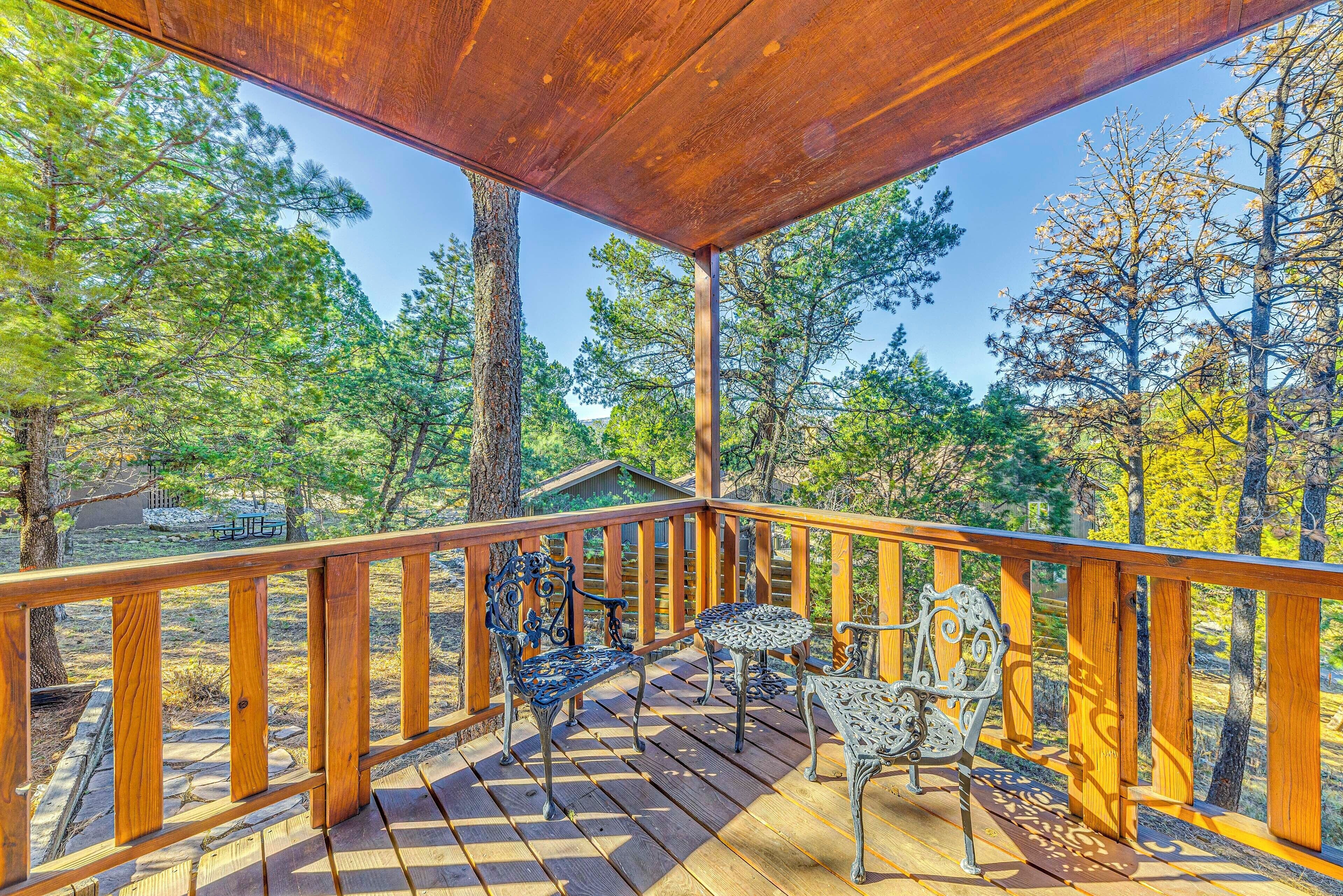 A wooden deck with a railing, two metal chairs, and a small table.
